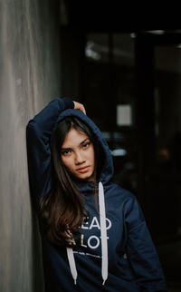 Portrait of young woman wearing hooded shirt standing outdoors