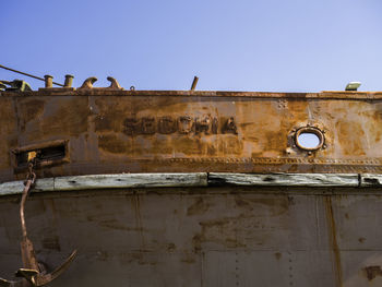 Low angle view of birds perching on old building against sky