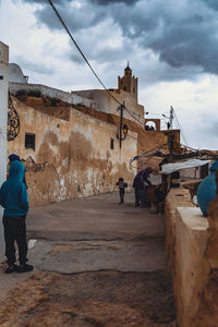 Rear view of people walking on street against sky