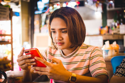 Young woman using mobile phone in restaurant