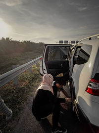 Rear view of man on car against sky