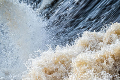 Close-up of flowing water, rapid water splashes of an white water river or stream, bubbly water