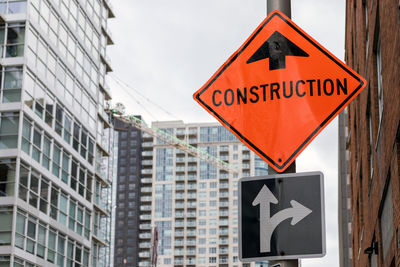 Construction orange sign near construction site against buildings