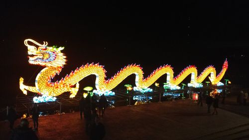 Illuminated carousel against sky at night