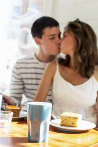 Couple kissing while sitting at restaurant table