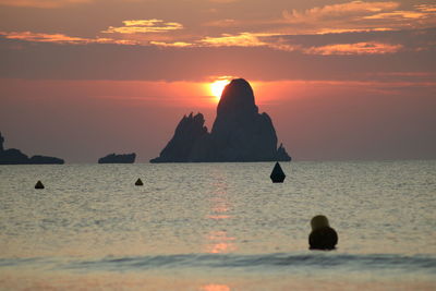 Scenic view of rocks in sea against sky during sunset