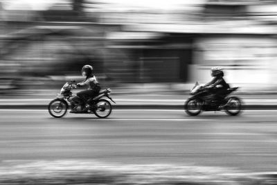 Side view of people riding motorcycle on road