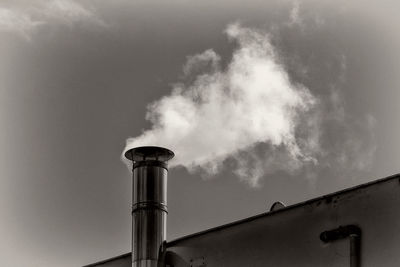 Low angle view of smoke emitting from chimney against sky