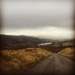 Country road against cloudy sky