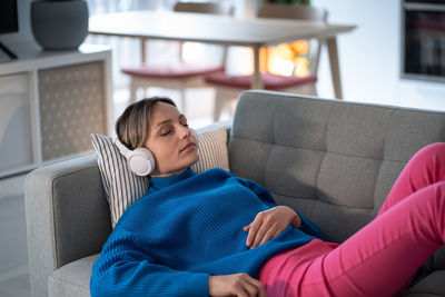 Attractive female in headset lying on soft couch resting nap relax. stress relief and mental health.