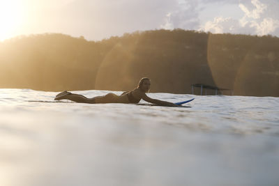 Female surfer in the ocean at sunset