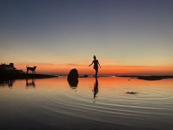 Silhouette people on beach against sky during sunset