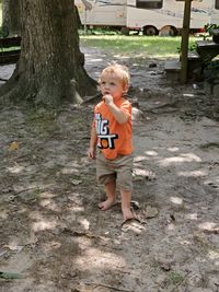 Full length of cute boy standing on tree