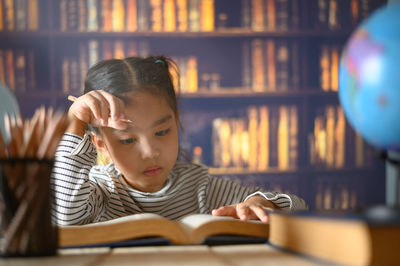 Portrait of boy with book on table