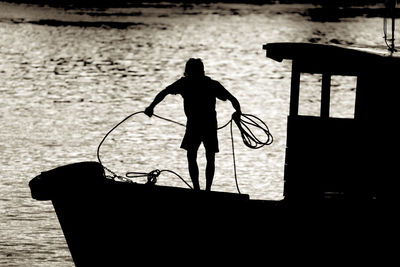 Rear view of silhouette man standing by sea