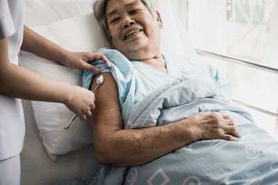 Midsection of nurse examining senior woman in hospital