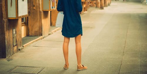 Low section of woman standing on footpath