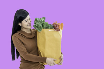 Mid adult woman holding ice cream against gray background