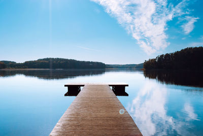 Wooden pier, sky reflected in water of lake baltieji lakajai in labanoras regional park