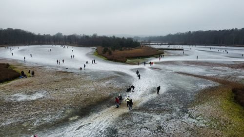 Scenic view of frozen lake against sky. ice skaters skating on natural ice