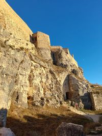 Low angle view of rock formations against clear blue sky