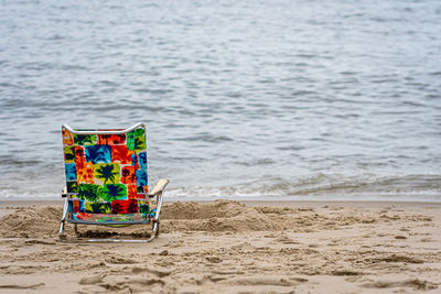 Lonely colorful chair on the beach near the ocean, summer vacation concept with copy space