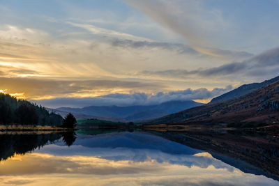 Reflection of mountains and dramatic cloudscape in a lake in snowdonia national park, north wales