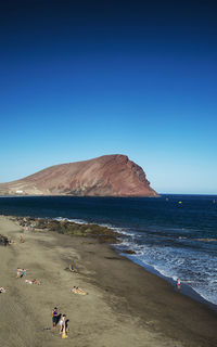 Scenic view of beach against clear blue sky