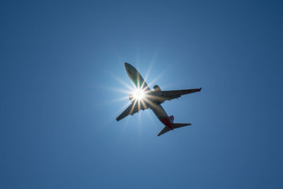 Low angle view of airplane against clear blue sky