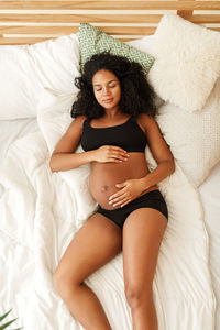 High angle view of pregnant woman wearing lingerie sleeping on bed at home