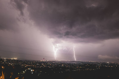 Panoramic view of lightning over city against storm clouds