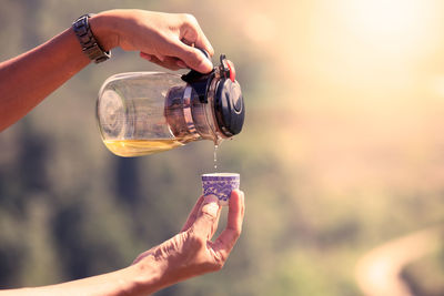 Cropped hands of person pouring tea in cup