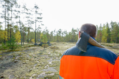 Rear view of man in forest against clear sky