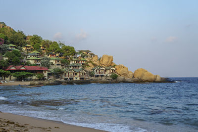 Houses by sea against sky