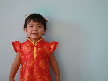 Portrait of cute girl standing against wall