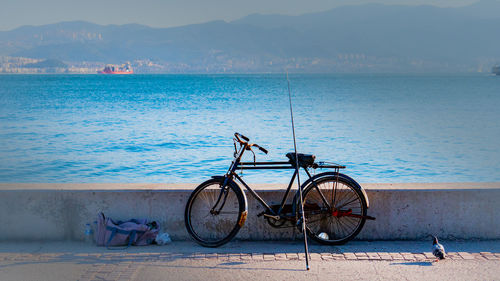 Bicycle by sea against sky