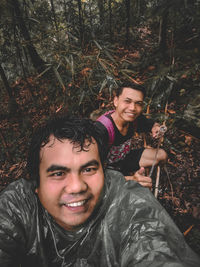 Portrait of smiling young man against trees