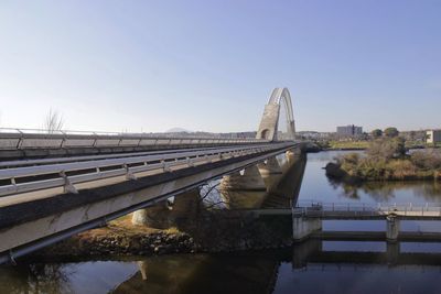 Bridge over river in city against clear sky