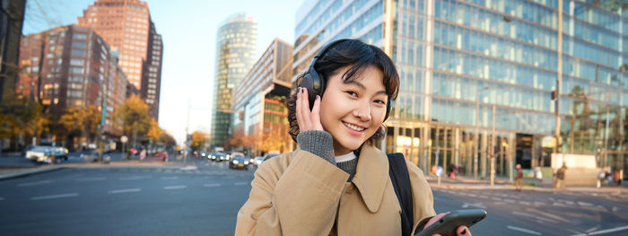 Side view of young woman standing against buildings