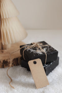 Blank paper tag, gift boxes with a string, snow and a paper christmas tree on the background.