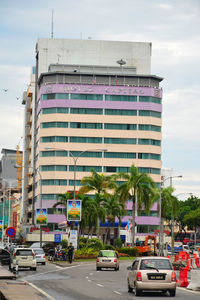 Cars on road by buildings against sky