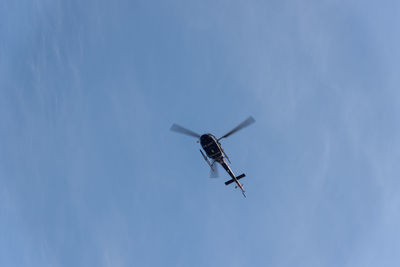 A helicopter flying against blue sky.