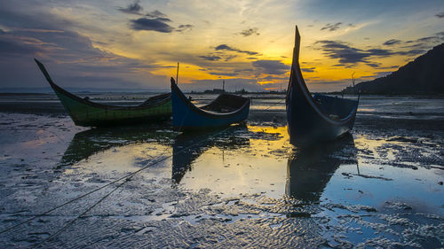 Boats moored on sea against sky during sunset