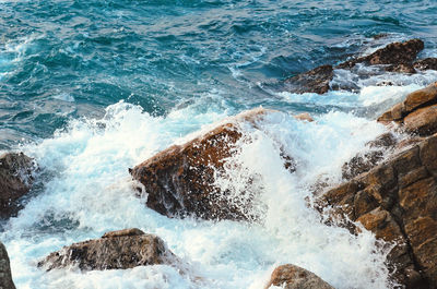 High angle view of waves splashing on rocks