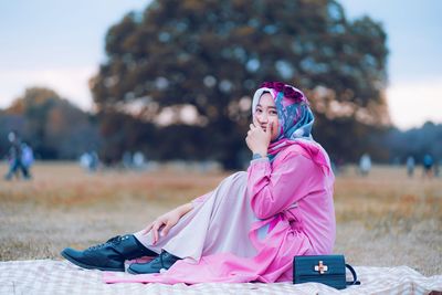 Woman looking at camera while sitting on field