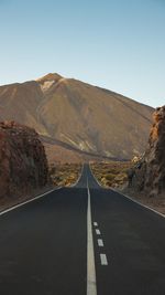 Road leading towards mountains against sky