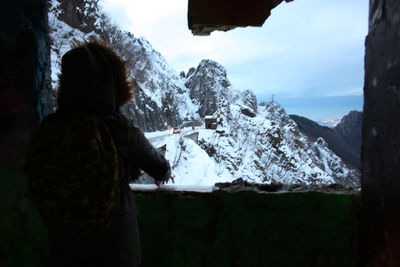 Rear view of person standing on snowcapped mountain