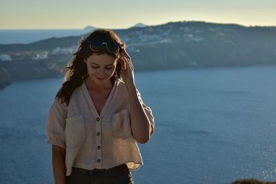 Young woman standing against sea