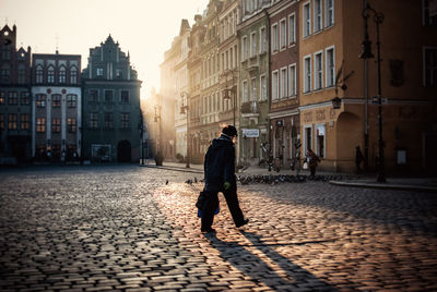 Man walking on street against buildings on sunny day