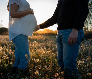 Midsection of couple standing on field